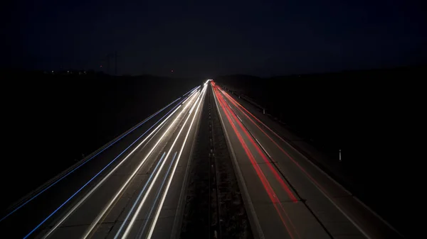 La escena urbana nocturna de movimiento borrosa las vías de luz que brillan hacia la ciudad. —  Fotos de Stock