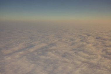 Yukarıdaki uçaktan alınan bulutlar akşam veya sabah güneşinin ılık altın rengi ışıklarıyla aydınlatılıyor.. 