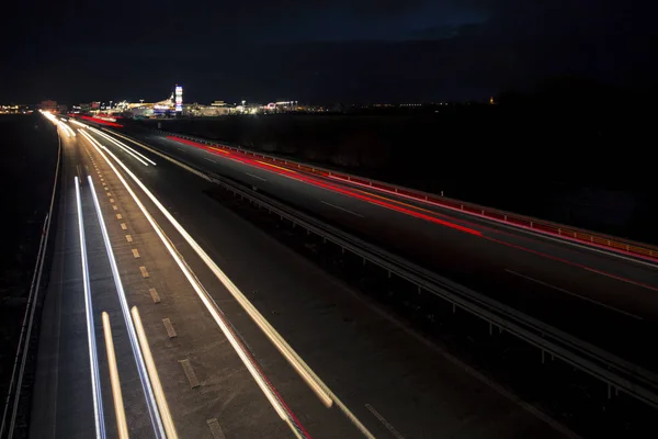 日没直後の都市への高速道路交通の暗闇に輝く動きのぼやけた光のトラック. ロイヤリティフリーのストック写真