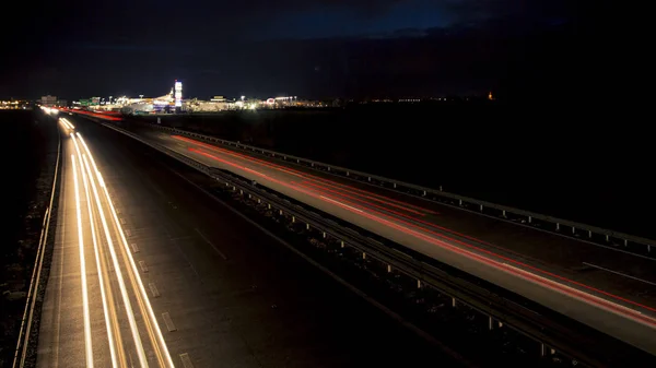 日没直後の都市への高速道路交通の暗闇に輝く動きのぼやけた光のトラック. ロイヤリティフリーのストック画像