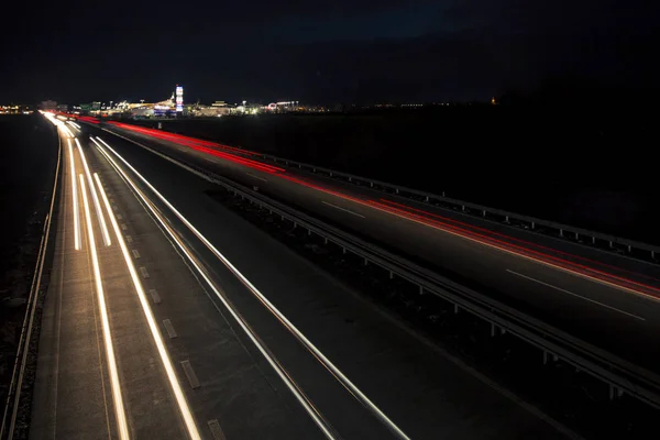 日没直後の都市への高速道路交通の暗闇に輝く動きのぼやけた光のトラック. ストック写真