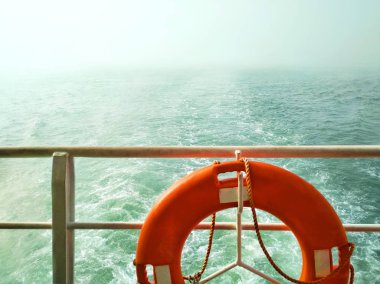 Bir teknenin arkasında dalgalar ile Masmavi deniz. Bir çit ve yaşam çemberi görünümü.