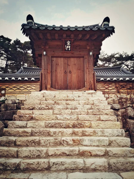 Gate to old wooden buddhist temple with big stone staircase and typical asian roof.