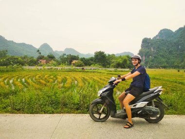 Arka planda pirinç tarlaları ile kamera bakarak bir scooter kız