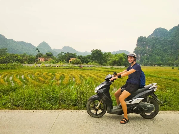 Arka planda pirinç tarlaları ile kamera bakarak bir scooter kız