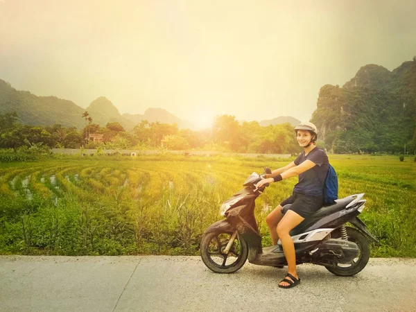 Backgrou pirinç tarlaları ile kamera bakarak bir scooter kız