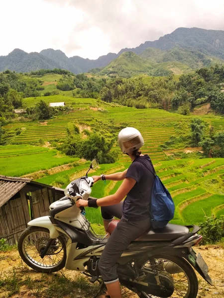 Lonely girl on motorbike enjoying view of rice fields