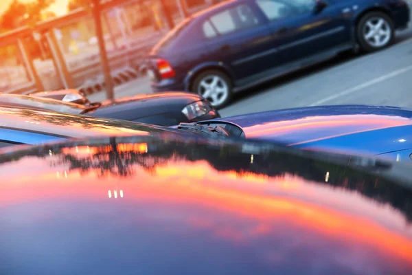 Pink sunset mirrored reflection on a metal car capote