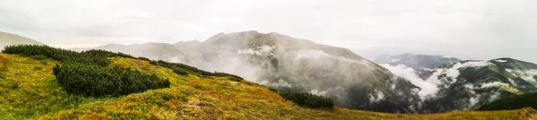 Wide panorama photo of high mountains surrounded by white clouds — Stock Photo, Image