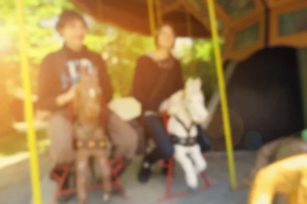 Visão turva de dois jovens adolescentes felizes desfrutando de montanhas-russas redondas durante o dia de verão em um parque de diversões — Fotografia de Stock