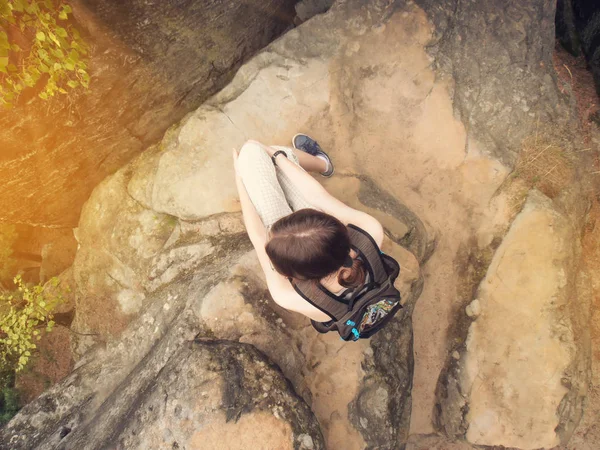 Chica joven desde arriba vista descansando en una montaña rocosa con mochila — Foto de Stock