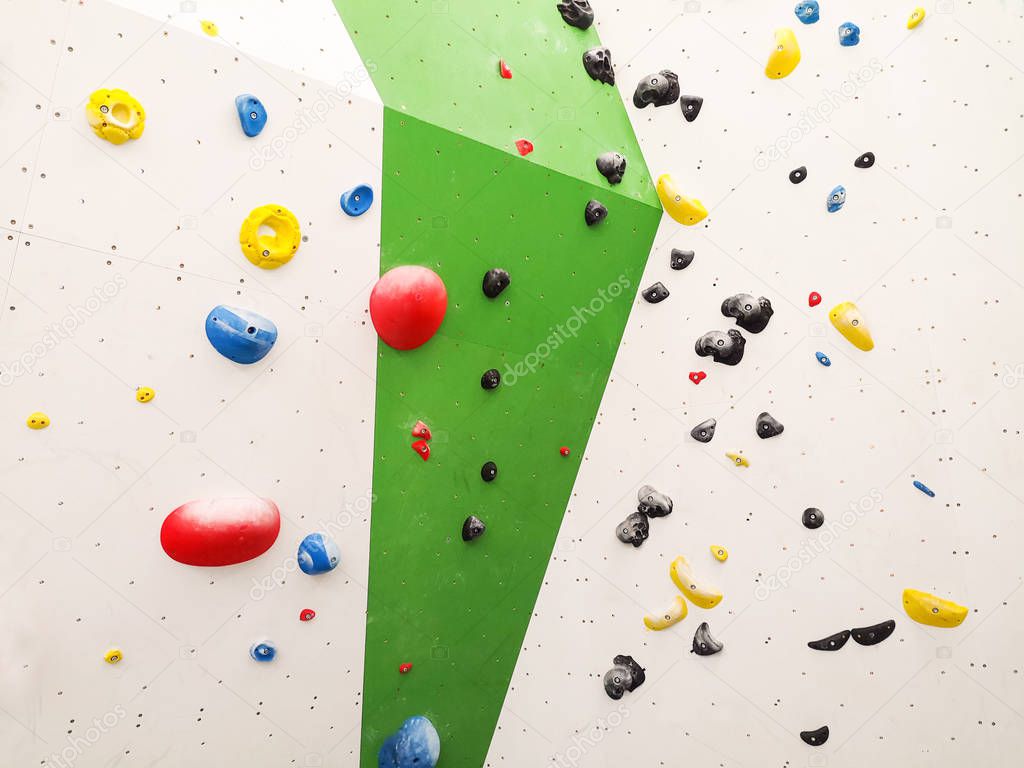 Abstract texture of green indoor climbing wall and colorful climbing handles
