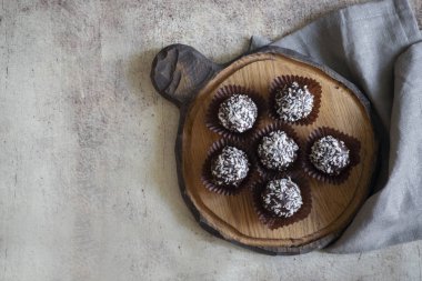 Iştah açıcı çikolatalı kek gri bir peçete ile ahşap bir Tahta üzerinde kağıt formlarda hindistan cevizi serpin