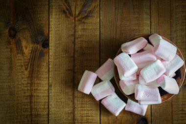 Ahşap bir arka plan üzerinde güzel bir tabak üzerinde Narin pembe ve beyaz marshmallow