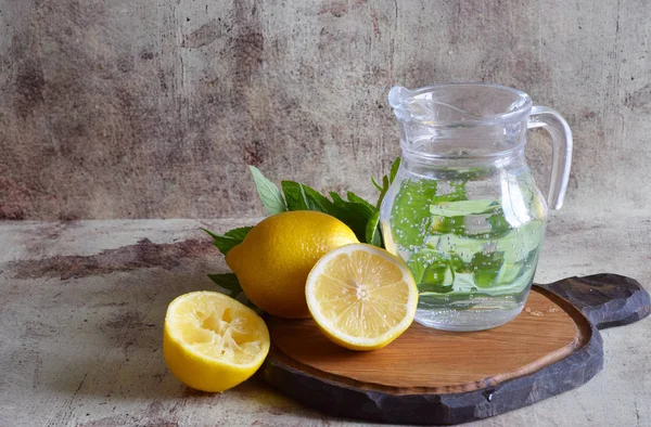 Cam bir kavanozda serin limonata, taze limon ve masada nane bir sprig.