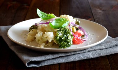 Domates, brokoli, karnabahar, soğan, Fesleğen ve susam iştah açıcı sebze salatası kahverengi ahşap bir masada yakın çekim fotoğraflandı