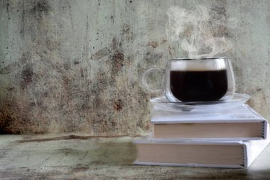 Güzel bir şeffaf Fincan sıcak kahve bir vintage gri arka plan üzerinde bulunan kitaplar, duruyor