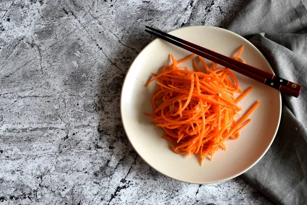 Spicy salad: Korean carrot. Vegetable salad on a beautiful plate on a gray background