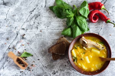 Kil tabakta gri bir masada domuz pirzolası ve bezelye çorbası. Kahverengi tabakta sıcak et suyu.