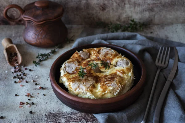 Eski gri bir arka planda kilden bir tabakta köfte ile iştah açıcı omlet.
