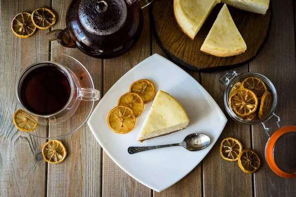 Tahta bir masada beyaz bir tabakta limonlu cheesecake dilimi.