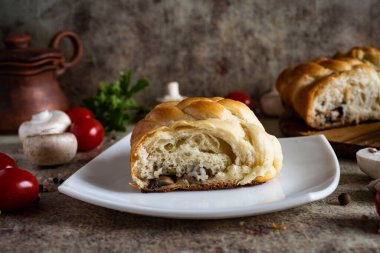 Beyaz bir tabakta pirinçli ve mantarlı maya keki. Arka planda mantarlı maya keki.