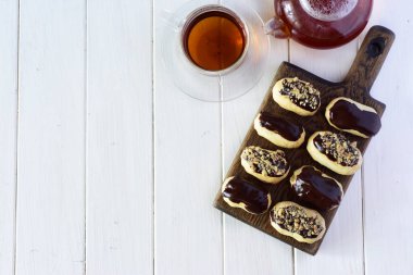 Çikolata kreması ve beyaz bir masanın üzerindeki tahta tahtada ceviz kaplı ekler..