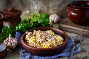 Öğle yemeği çok lezzetli: gri arka planda kil tabakta mantarlı haşlanmış patates.