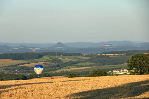 Globo de aire caliente sobre el campo con cielo azul frente a la saxonia Suiza —  Fotos de Stock