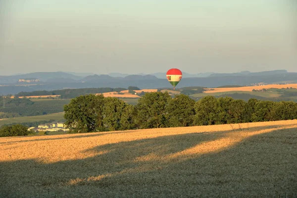 Balon na gorącym powietrzu na polu z błękitnym niebem przed Saksonii Szwajcarii — Zdjęcie stockowe