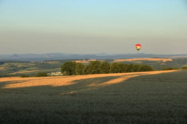 Balon na gorącym powietrzu na polu z błękitnym niebem przed Saksonii Szwajcarii — Zdjęcie stockowe