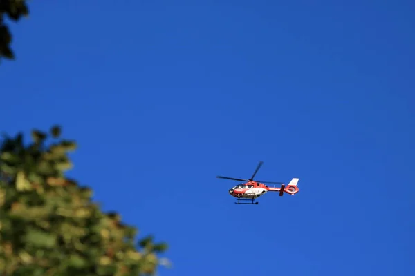 Helicóptero de rescate rojo moviéndose en el cielo azul con hélice borrosa —  Fotos de Stock