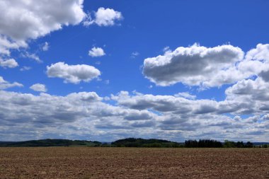 Kırsal bölgedeki pullu ya da pullu tarlalar ve Ufuk üzerindeki bulutlarla mavi gökyüzü