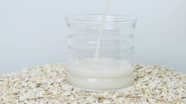 Овсяное молоко в прозрачной чашке, налитое в стекло — стоковое видео