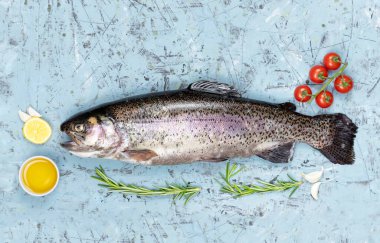 Bağırsakları deşilmiş kırmızı balık alabalığı. Baharatlı taze alabalık. Yakınlarda: limon, domates, yağ, limon, biber, soğan, tuz. Boşluğu kopyala.