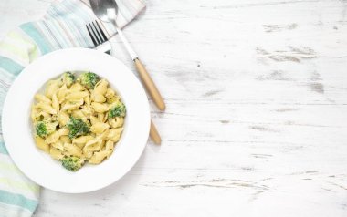 Yeşil sebzeli makarna, brokoli, erimiş peynir ve beyaz masadaki kremalı sos. Üst Manzara. Boşluğu kopyala.