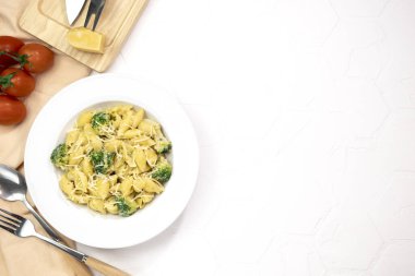 Yeşil sebzeli makarna, brokoli, erimiş peynir ve beyaz masadaki kremalı sos.. 