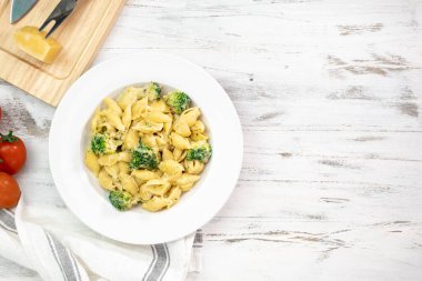 Yeşil sebzeli makarna, brokoli, erimiş peynir ve beyaz masadaki kremalı sos.. 