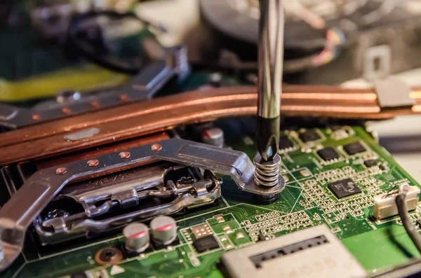 Technical support worker unspins the cover of the computer monoblock with a screwdriver