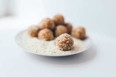 Bulanık bir arka plan üzerinde beyaz bir tabak üzerinde bir fındık kırıntısı meyve topları