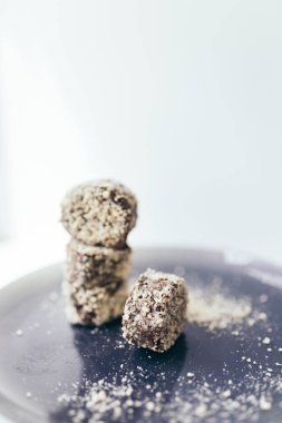 Bulanık bir arka plan ile mor bir tabak üzerinde bir fındık kırıntısı yuvarlak çikolatalı kek