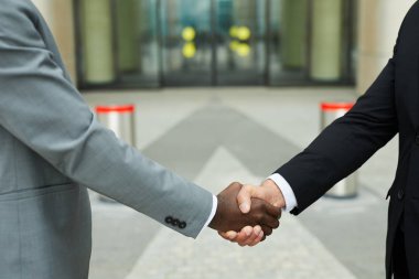 Çok ırklı iş adamlarının şehirde dışarıda dururken el sıkışması.