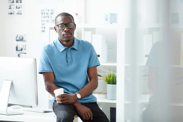 テーブルに座るカジュアルな服装の若いアフリカ人実業家の肖像とオフィスでコーヒーブレイク中に使い捨てカップからコーヒーを飲む — ストック写真