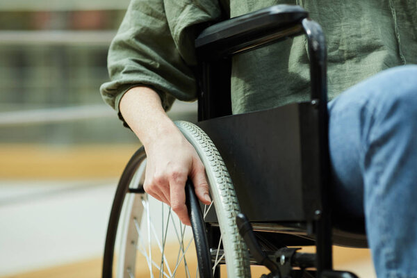 Крупный план молодой женщины, сидящей в инвалидном кресле и держащей колесо
