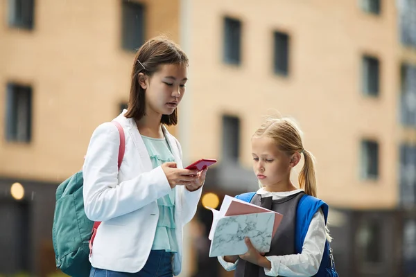 Asiatico Studentessa Utilizzando Cellulare Con Minore Sorella Guardando Libri Mentre — Foto Stock