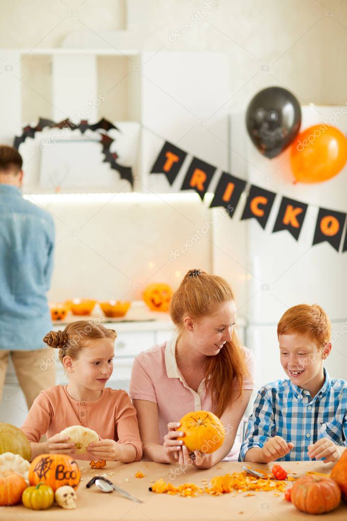 Happy family at the table making crafts from pumpkins preparing together for Halloween party
