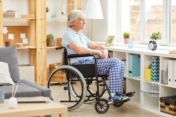 Tekerlekli Sandalyede Oturan Pencereden Dışarı Bakan Yaşlı Engelli Bir Adam — Stok fotoğraf