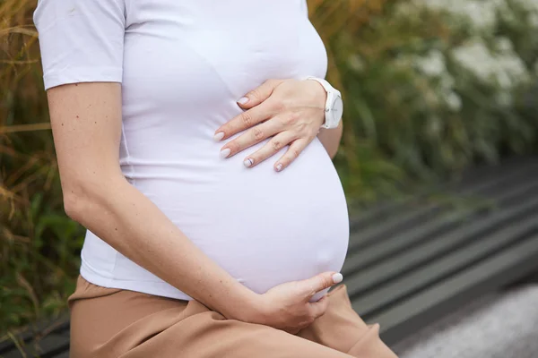 Close Woman White Shirt Embracing Pregnant Belly While Sitting Bench — Stock Photo, Image