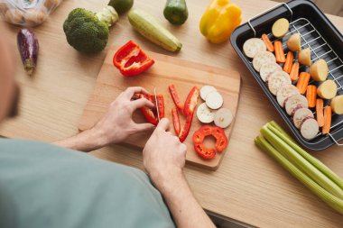 Adam akşam yemeği için ızgara sebze hazırlıyor.