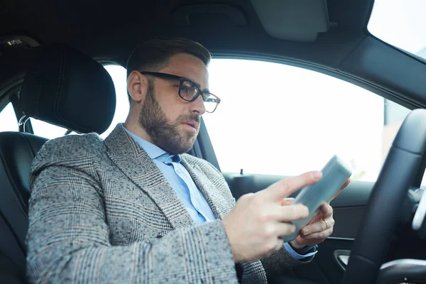 Mężczyzna korzystający z tabletu w samochodzie — Zdjęcie stockowe